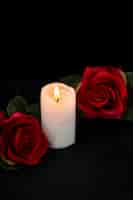 Kostenloses Foto vorderansicht des kleinen grabes mit kerze und roten rosen auf schwarz