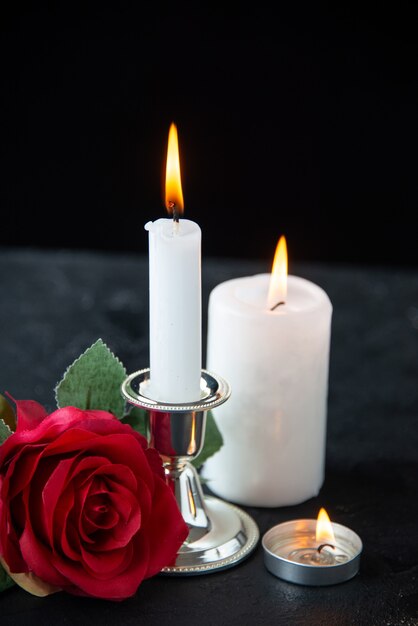 Vorderansicht des kleinen Grabes mit roter Rose und Kerze auf Schwarz