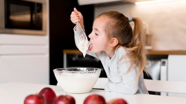 Kostenloses Foto vorderansicht des kleinen mädchens, das zu hause kocht