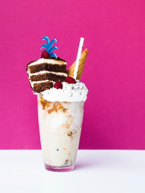 Vorderansicht des köstlichen Milshakes mit Eistüte und Kuchen