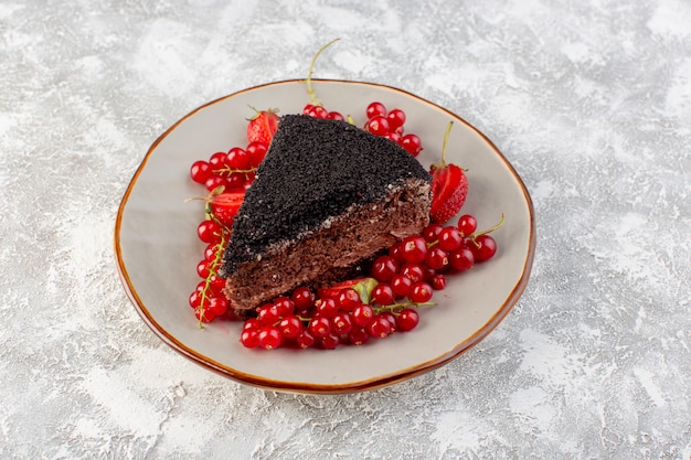 Vorderansicht des köstlichen Schokoladenkuchens, der mit Schokoladencreme und frischen roten Preiselbeeren geschnitten wird