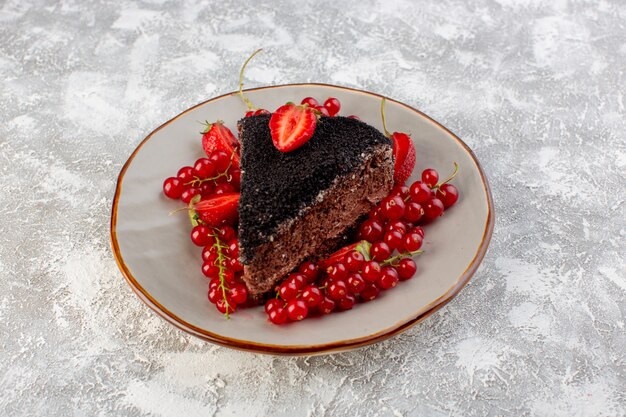 Vorderansicht des köstlichen Schokoladenkuchens, der mit Schokoladencreme und frischen roten Preiselbeeren geschnitten wird