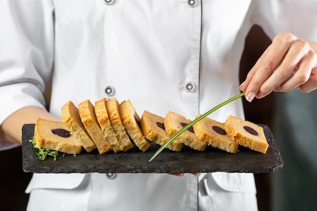 Kostenloses Foto vorderansicht des küchenchefs, der einen köstlichen essensteller hält