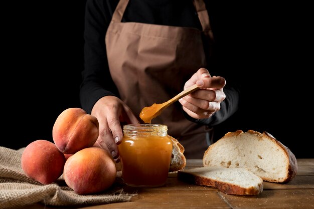 Vorderansicht des Küchenchefs mit Glas Pfirsichmarmelade