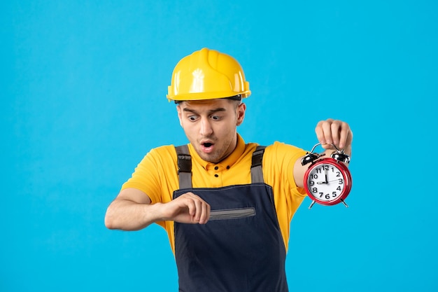 Vorderansicht des männlichen Arbeiters in der Uniform mit den Uhren, die spät auf dem Blau sind