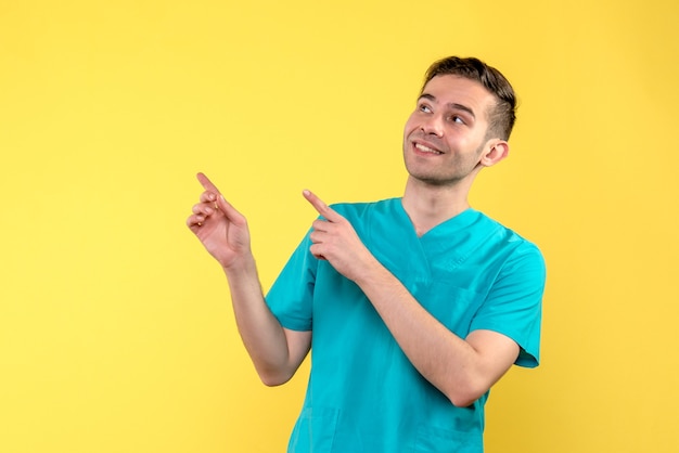 Vorderansicht des männlichen Arztes, der auf gelber Wand lächelt