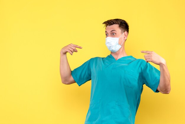 Vorderansicht des männlichen Arztes in der Maske auf gelber Wand