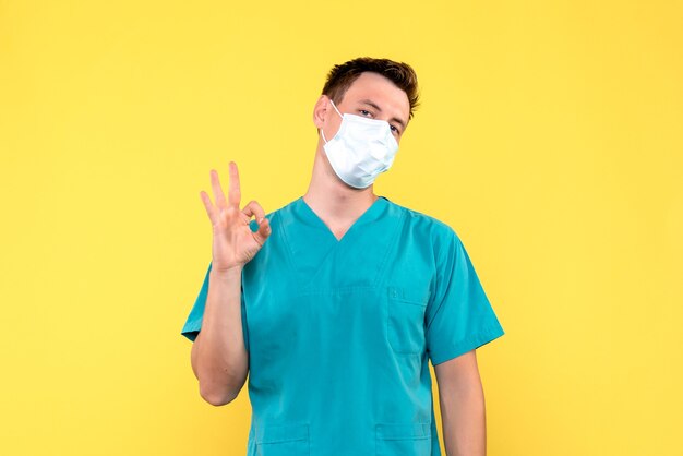 Vorderansicht des männlichen Arztes in der sterilen Maske auf dem männlichen Sanitäter des gelben Bodenemotionskrankenhauses