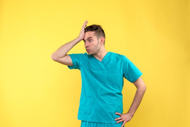 Vorderansicht des männlichen Arztes mit dem traurigen Gesicht auf gelber Wand