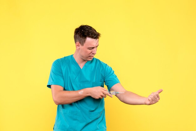 Vorderansicht des männlichen Arztes unter Verwendung der großen Injektion auf gelber Wand