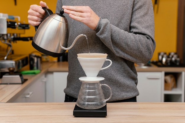 Kostenloses Foto vorderansicht des männlichen barista, der heißes wasser über kaffeefilter gießt