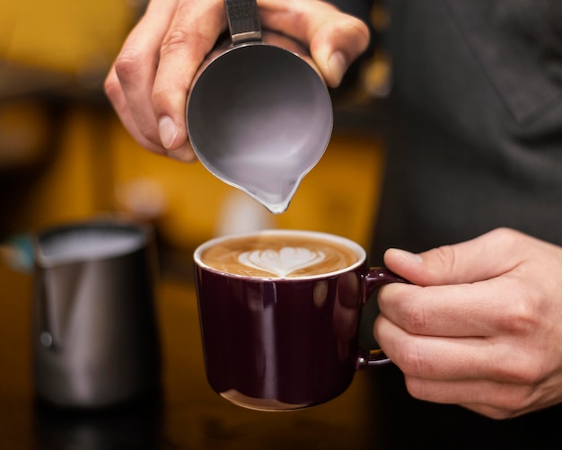 Vorderansicht des männlichen Barista, der Kaffee in Tasse gießt