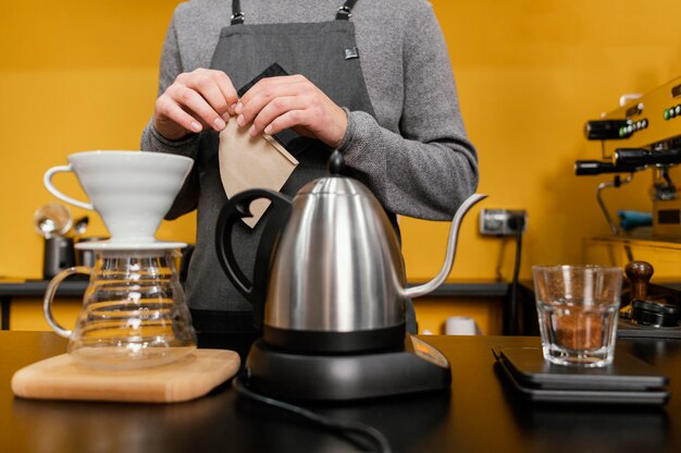 Vorderansicht des männlichen Barista mit der Schürze, die Kaffee macht