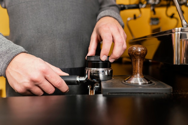 Vorderansicht des männlichen Barista unter Verwendung der professionellen Kaffeemaschinenschale