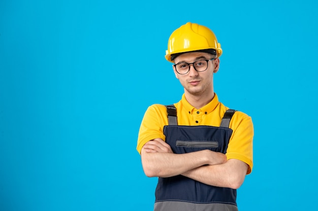 Vorderansicht des männlichen Baumeisters in der Uniform und im Helm auf der blauen Wand
