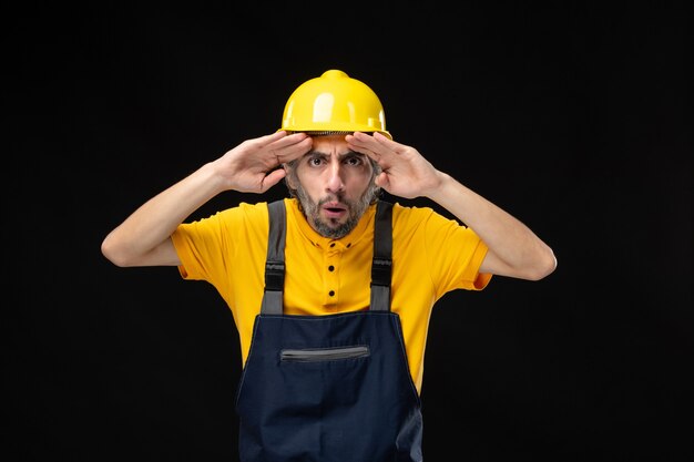 Vorderansicht des männlichen Baumeisters in Uniform an der schwarzen Wand