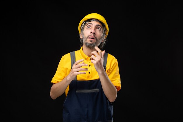 Vorderansicht des männlichen Baumeisters in Uniform an der schwarzen Wand