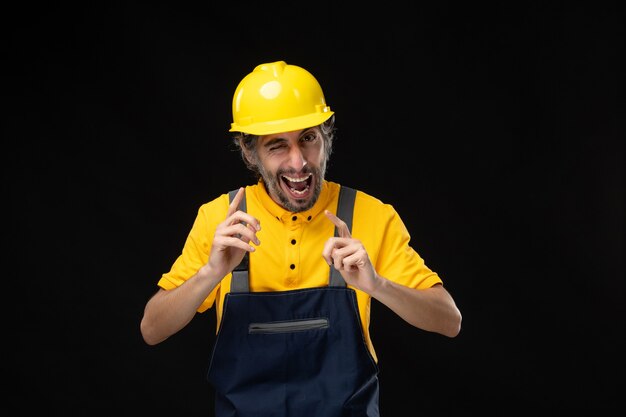 Vorderansicht des männlichen Baumeisters in Uniform an der schwarzen Wand