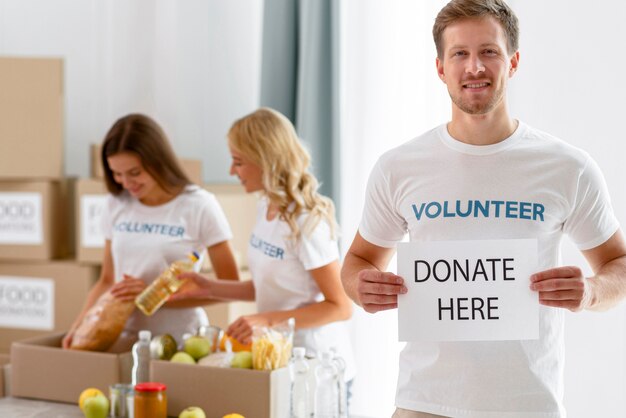 Vorderansicht des männlichen Freiwilligen, der Plakat mit Spendenanweisungen hält
