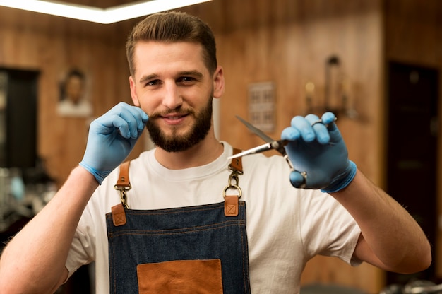 Vorderansicht des männlichen Friseurs, der eine Schere im Friseursalon hält