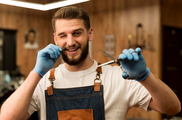 Vorderansicht des männlichen Friseurs, der eine Schere im Friseursalon hält