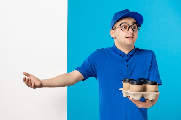 Vorderansicht des männlichen Kuriers mit Kaffee auf dem Blau