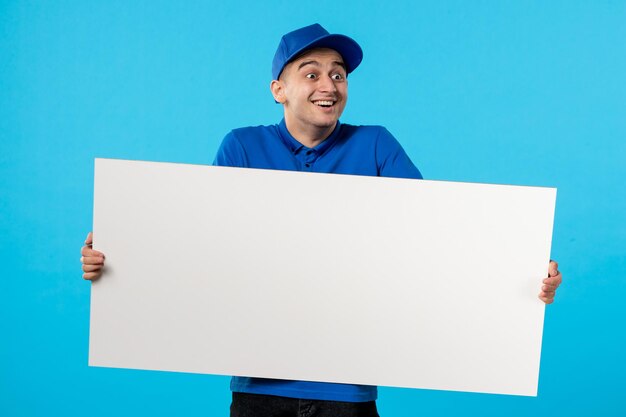 Vorderansicht des männlichen Kuriers mit weißem Schreibtisch auf dem Blau