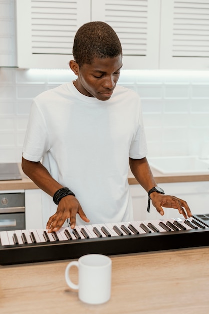 Vorderansicht des männlichen Musikers zu Hause, der elektrische Tastatur spielt
