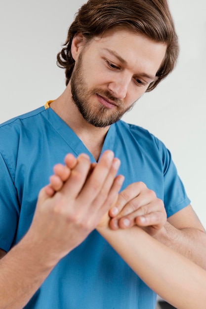 Kostenloses Foto vorderansicht des männlichen osteopathischen therapeuten, der das handgelenk der patientin prüft