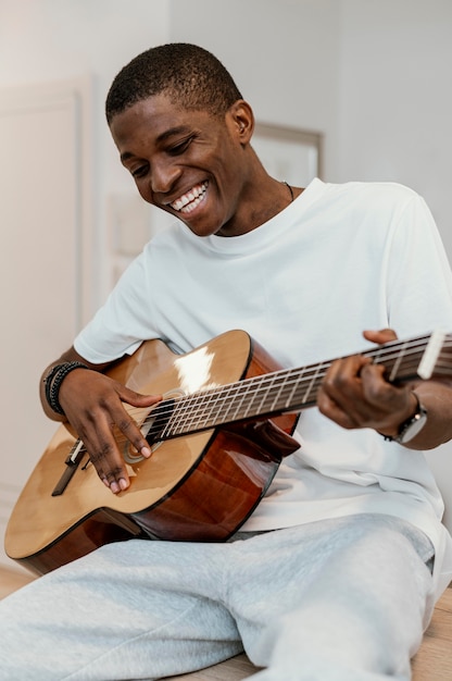 Kostenloses Foto vorderansicht des männlichen smiley-musikers zu hause, der gitarre spielt