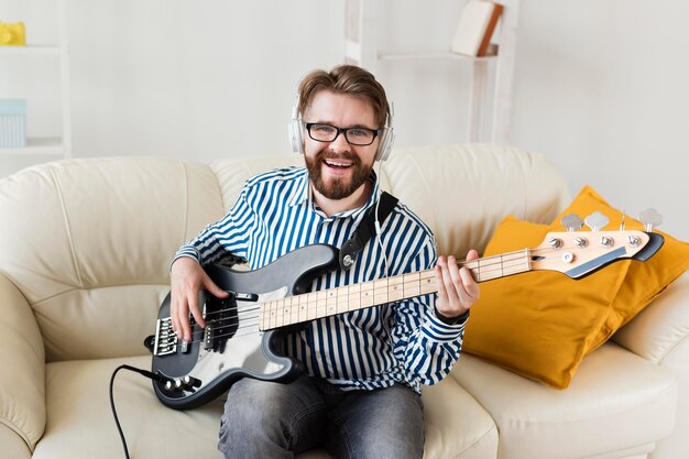 Vorderansicht des Mannes auf Sofa mit E-Gitarre