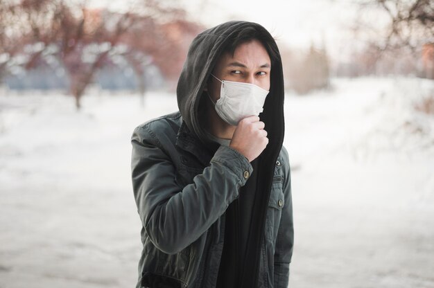 Vorderansicht des Mannes, der beim Tragen einer medizinischen Maske aufwirft