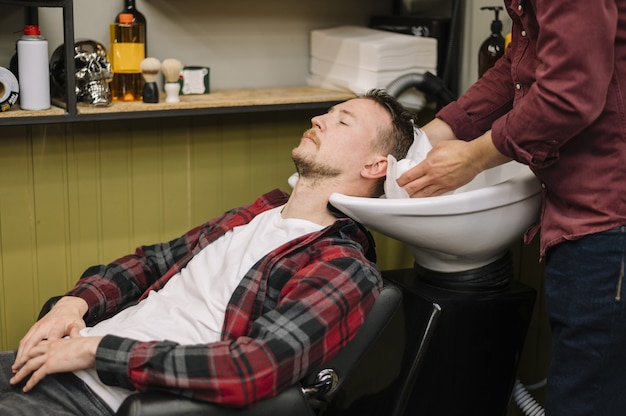 Vorderansicht des Mannes, der Haare am Friseurladen wäscht