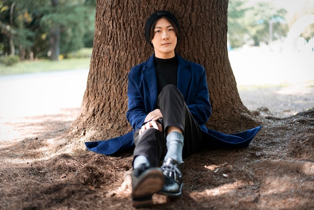 Kostenloses Foto vorderansicht des mannes, der im park gegen baum aufwirft