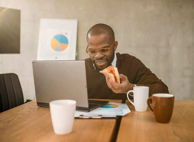 Vorderansicht des Mannes, der Pizza während einer Bürobesprechungspause hat