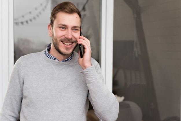 Vorderansicht des Mannes in der Strickjacke sprechend am Telefon