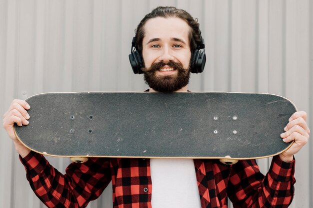 Kostenloses Foto vorderansicht des mannes skateboard halten