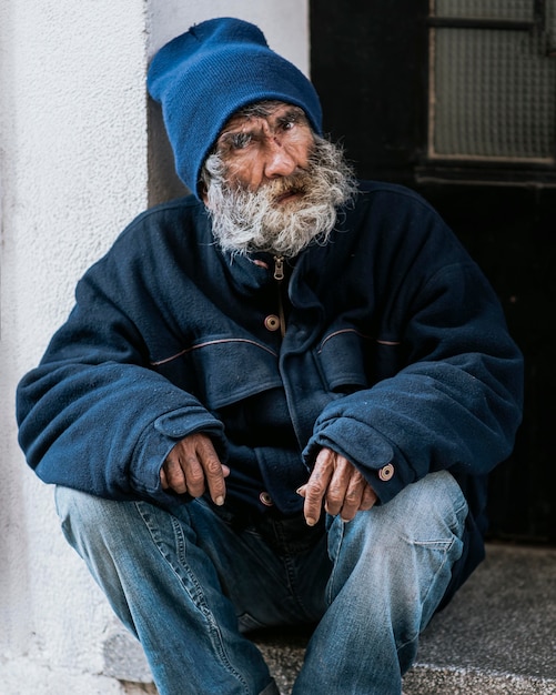 Vorderansicht des Obdachlosen mit Bart vor der Haustür