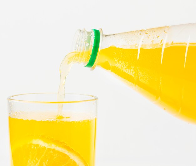 Vorderansicht des Orangensaftes, der in Glas von Flasche gegossen wird