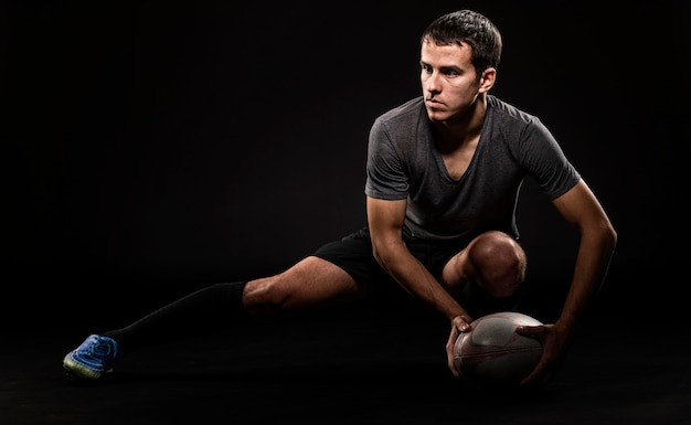 Vorderansicht des schönen athletischen männlichen Rugbyspielers, der Ball hält