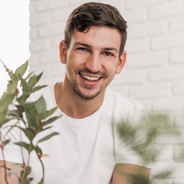 Vorderansicht des Smiley-Mannes, der neben Pflanzen sitzt