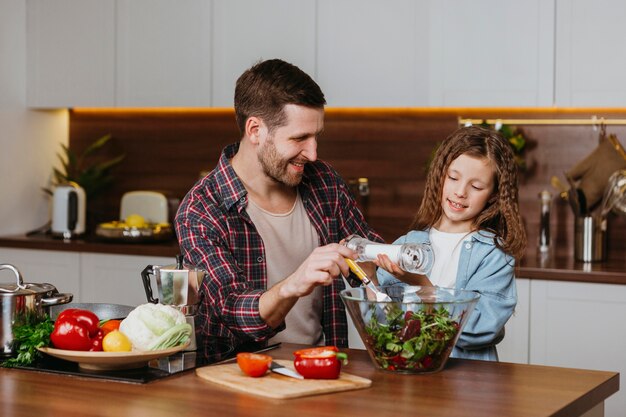 Vorderansicht des Smiley-Vaters mit Tochter, die Essen in der Küche zubereitet