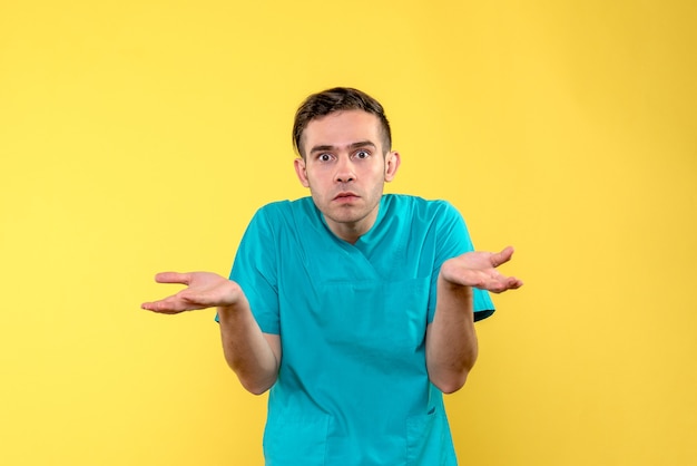 Vorderansicht des verwirrten Mannes des männlichen Arztes auf gelber Wand