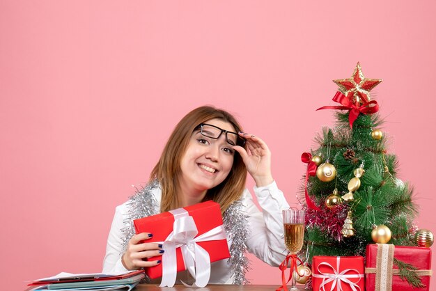 Vorderansicht des weiblichen Arbeitnehmers, der Geschenk auf Rosa hält