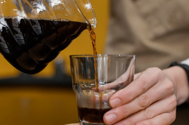 Vorderansicht des weiblichen Barista, der Kaffee in transparentes Glas gießt