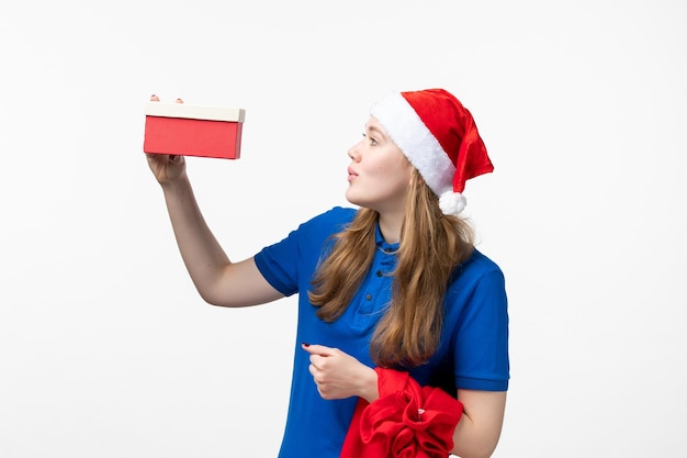 Vorderansicht des weiblichen Kuriers mit Feiertagsgeschenk an der weißen Wand