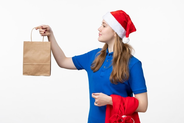 Vorderansicht des weiblichen Kuriers mit Feiertagsgeschenk an der weißen Wand