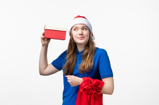 Vorderansicht des weiblichen Kuriers mit Feiertagsgeschenk auf weißer Wand