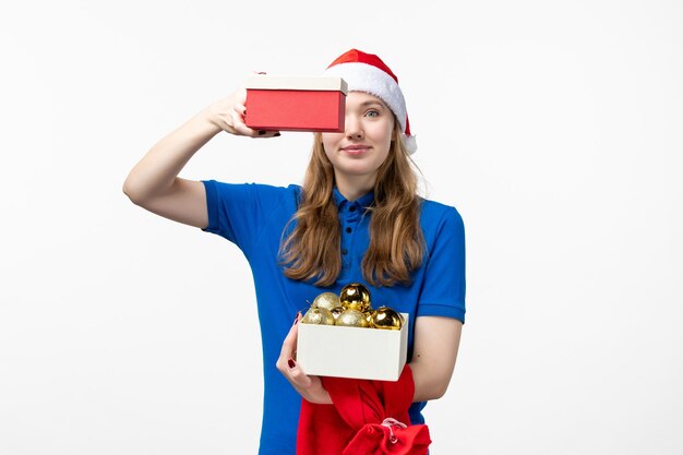 Vorderansicht des weiblichen Kuriers mit Geschenk und Spielzeug auf weißer Wand