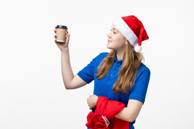 Vorderansicht des weiblichen Kuriers mit Kaffeetasse auf weißer Wand